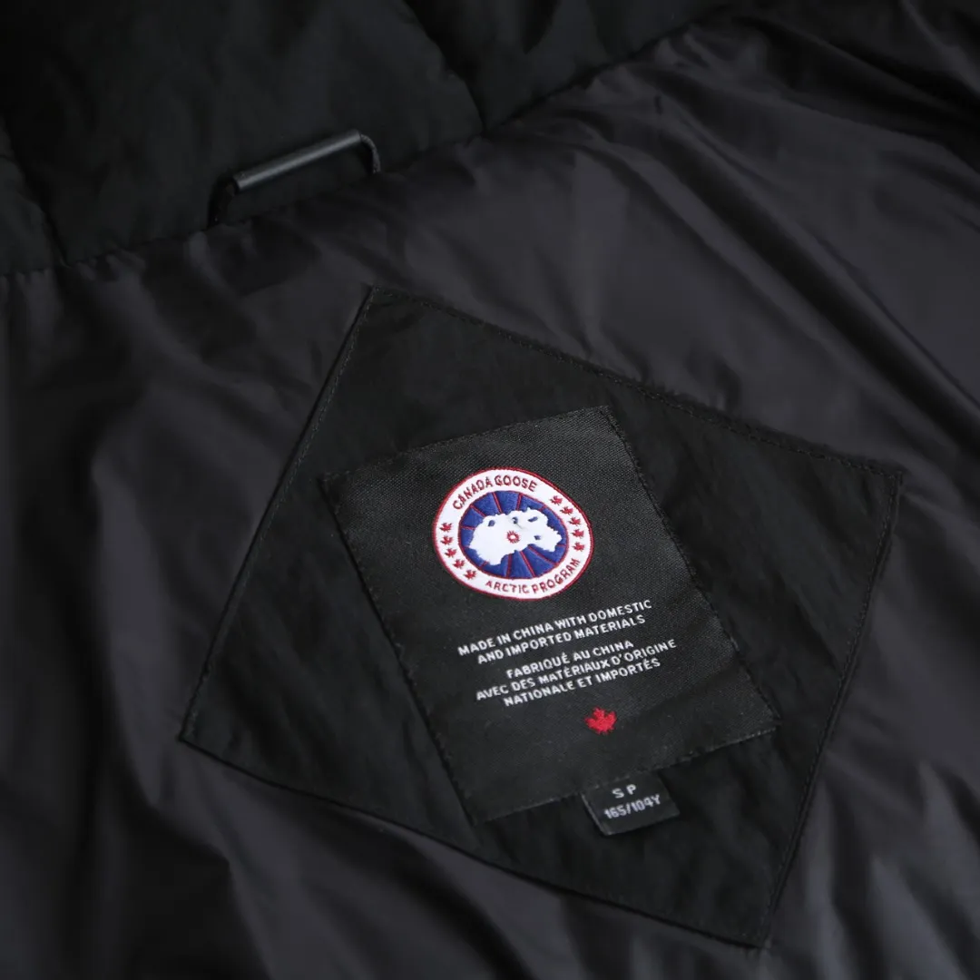 P980 Canada Goose hooded down jacket Fabric selection: Weaved with 400T high-count yarn. After special water-repellent treatment, the surface forms a lotus leaf effect - raindrops will slide down in beads, and snow particles will fall off when touched. The tear resistance reaches 200N (approximately 20kg load-bearing), the light gray matte texture breaks the stereotype of "outdoor clothing = hardcore", and the soft luster presents a high-end matte effect under urban neon lights, seamlessly switching scenes from ski resorts to CBD office buildings.  Process 1: Use polyester woven ribbons as the base, and use high-precision computer embroidery to decorate the brand letters on the ribbons. The edges of the pattern are clear, the stitches are fine and even, and multiple layers of embroidery threads are stacked to enhance the three-dimensional effect.  Process 2: Precision thread reinforcement to prevent velvet drilling and ensure that the fluffy and resilient elasticity lasts as new.  Details: The embedded cuffs are three-dimensionally woven to form a "wavy" elastic structure, forming natural folds when fitting the wrist, increasing the contact area with the skin, thus improving the windproof effect. At the same time, micro-velvet treatment is added to the inside of the cuffs, which feels like a second layer of skin and avoids friction on the skin from metal zippers or hard fabrics.  90 national standard high-quality white duck down: selected high-loft down, weighing 240g, light and warm, with excellent temperature locking performance and good resilience.  Accessories: 1:1 customized armband, 1:1 customized zipper pendant, 1:1 customized elastic buckle, etc. SIZE: S M L XL